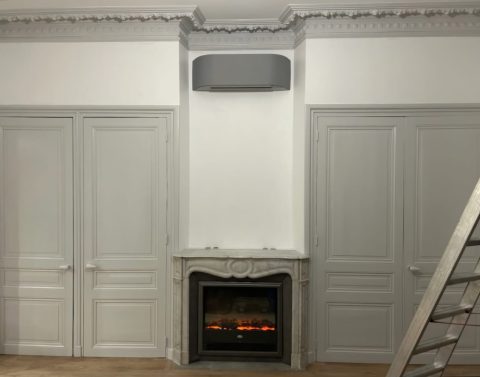 Climatisation réversible gris anthracite au-dessus d'une cheminée en marbre, appartement ancien à Charlieu